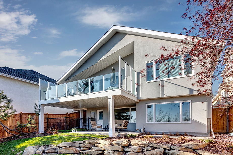 An exterior photo of a beautiful home renovation in Calgary, with the sun shining, a blue sky and a tree on the right.